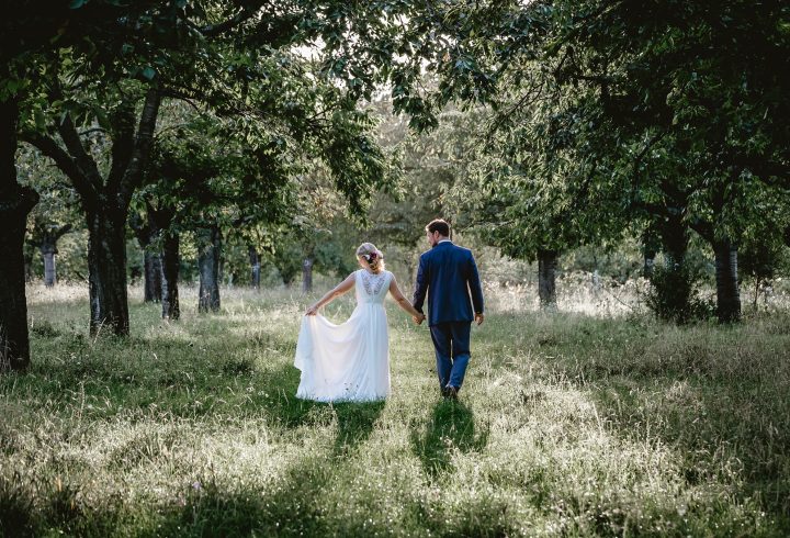 Bride and groom walking through a wooded area