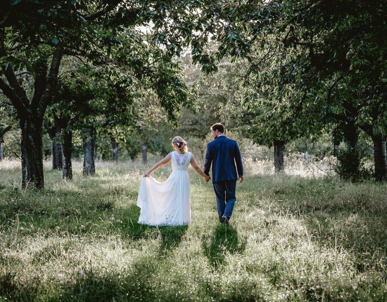 Bride and groom walking through a wooded area